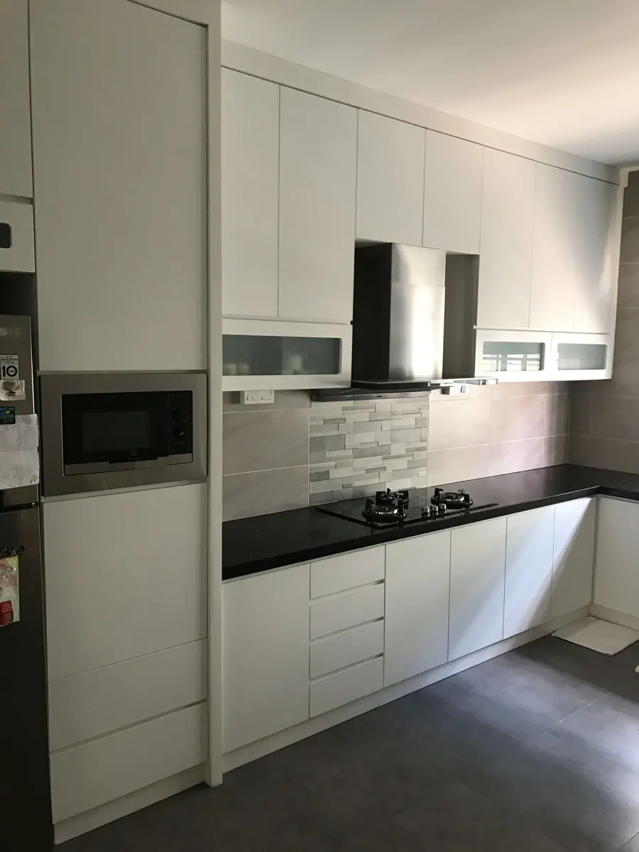 White kitchen cabinets with a black worktop, built-in microwave tower and wall cabinets around the cooker hood