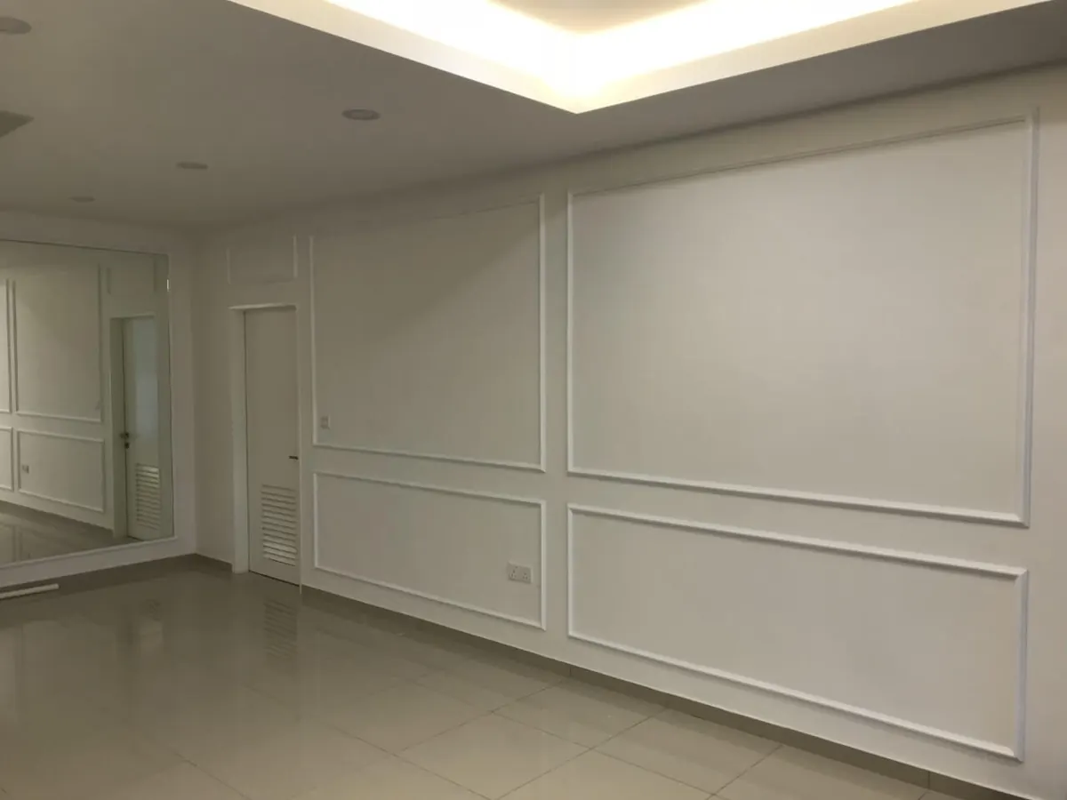 Ruang tamu rumah baru yang kosong dengan panel moulding putih di dinding, siling plaster berlampu dan cermin besar