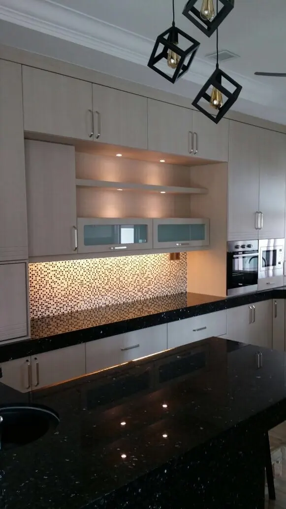 Dapur custom dengan oven dan microwave terbina dalam, rak terbuka dan table top granit hitam