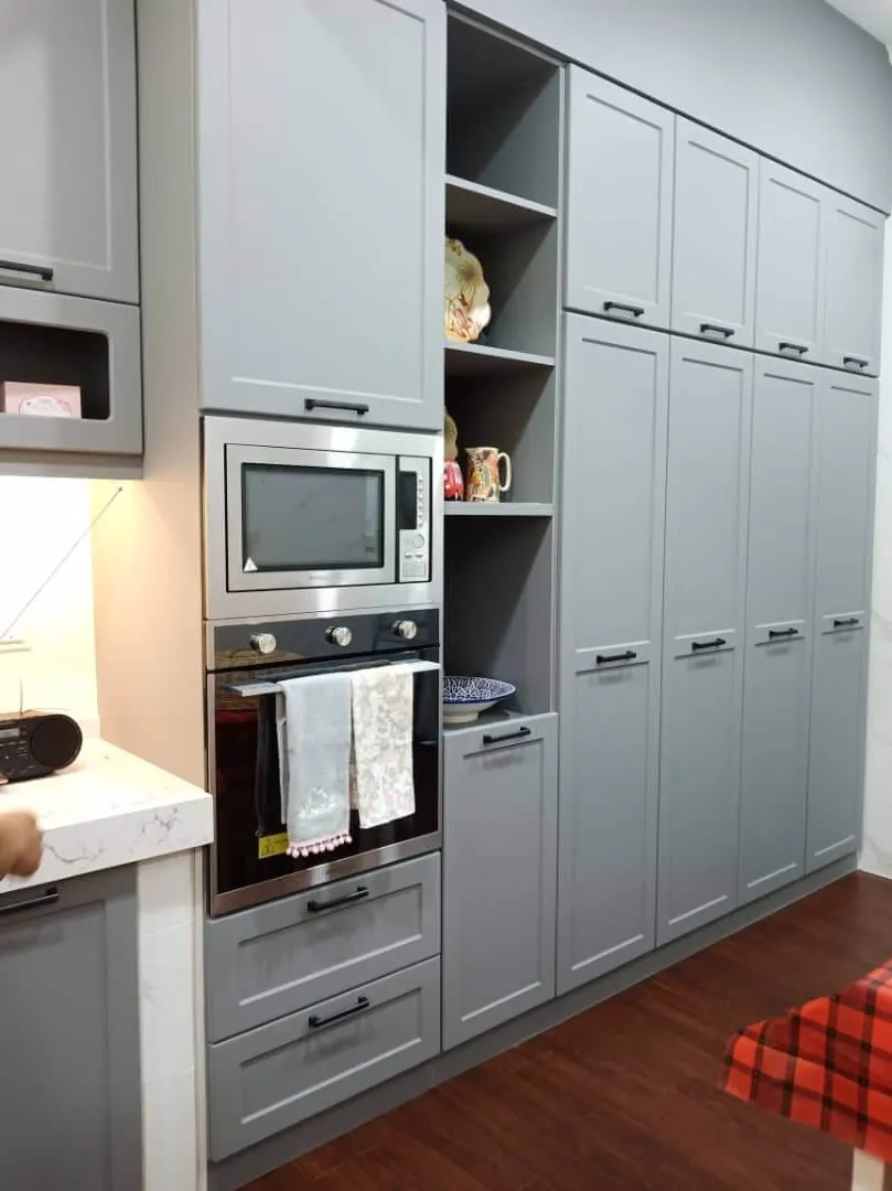 Kabinet tinggi shaker kelabu dengan oven, microwave terbina dalam, rak pameran terbuka dan pintu pantri