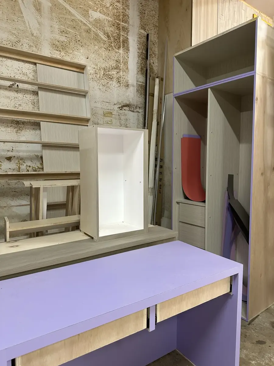A lilac study desk with drawers, a white cabinet box and a wardrobe carcass in our workshop