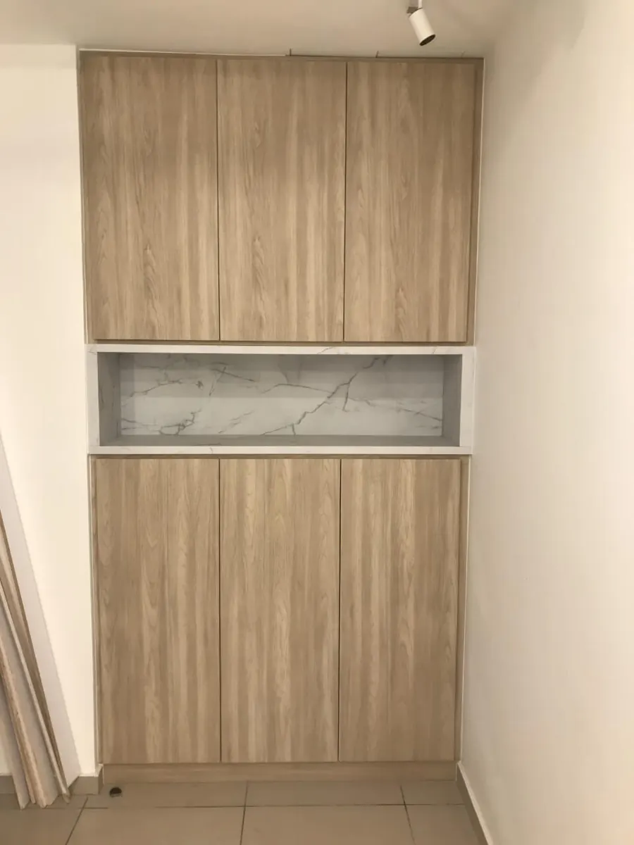 Wood-grain tall cabinet with a white marble-look open niche in the middle, fitted into a wall recess