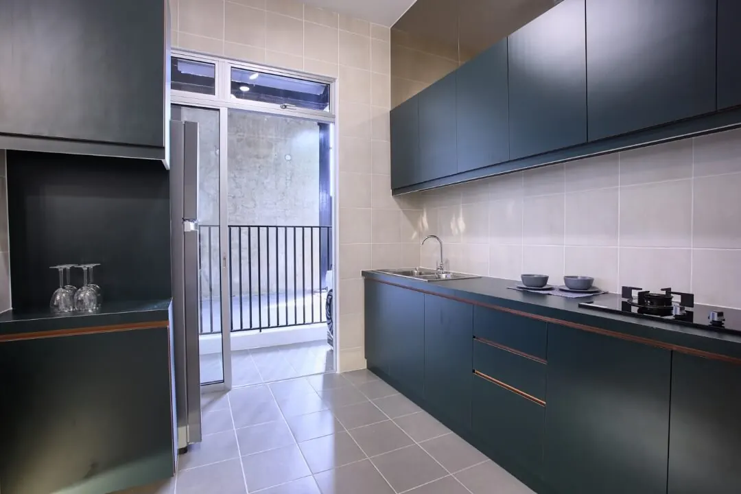 Dark green wet kitchen with sink and gas hob on one long run, a fridge and a door leading to the back yard
