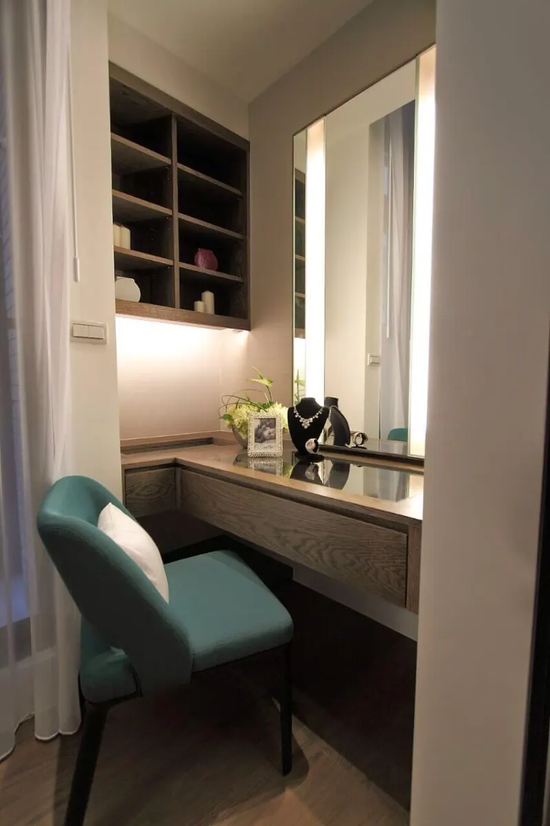 Built-in vanity desk with drawer, lit mirror and open shelves above in a bedroom corner